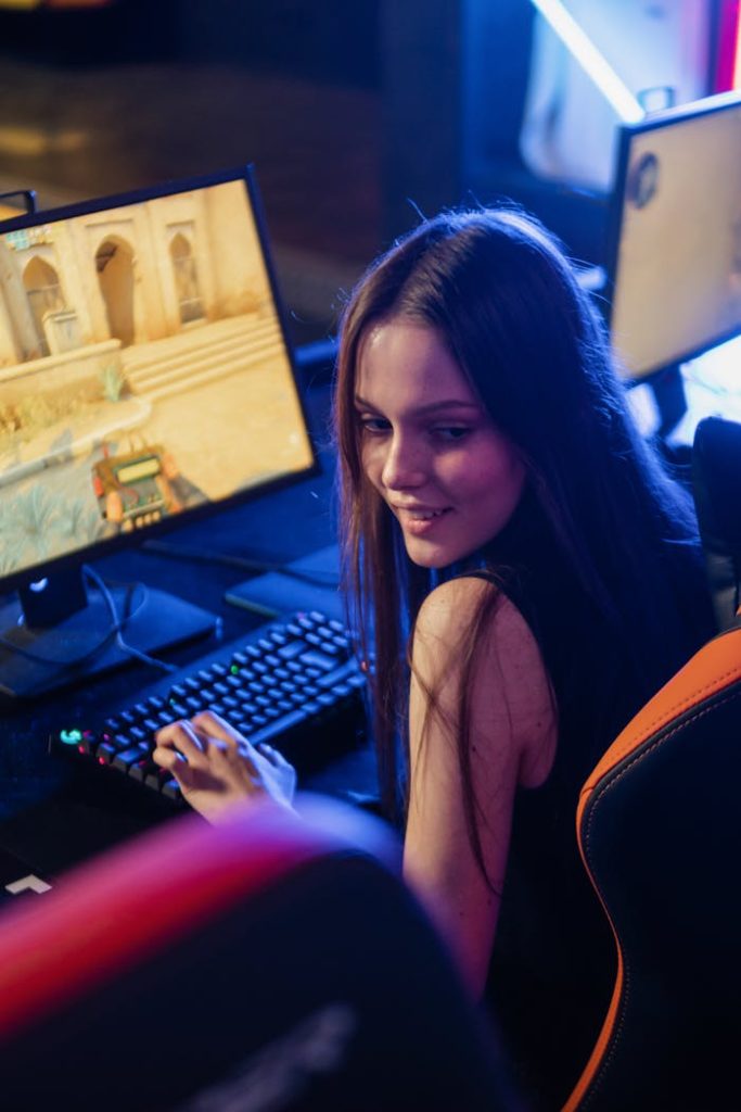 Teenage girl smiling while engaged in a computer gaming session indoors.